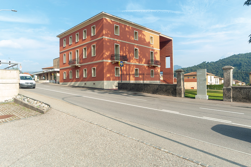 Ein brutalistischer Bau aus rotem Beton macht den historischen Sitz der Gemeinde Bioggio zeitgemäss. Architekten Bronner und Bruno